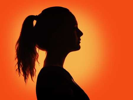  woman portrait profile  in silhouette shadow on studio  orange backgroundの写真素材