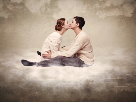 Young couple enamoured, flying over a city on a cloudの写真素材