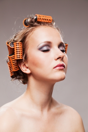 Stylish girl portrait with fashion makeup and hair curlers, isolated on grey background, hair and beauty treatment concept の写真素材