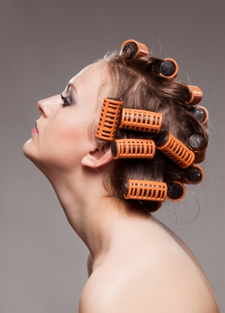 Stylish girl portrait with fashion makeup and hair curlers, isolated on grey background, hair and beauty treatment concept の写真素材