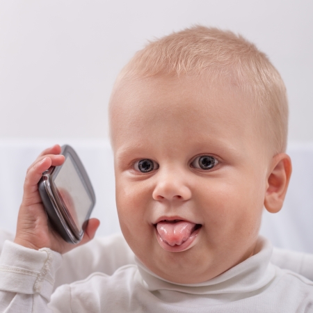 Little Boy with Phone Puts out the Tongue, close-upの写真素材