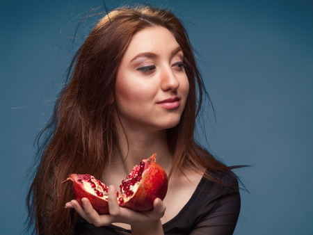 Portrait girl with pomegranate on blueの写真素材