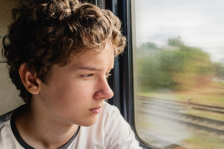 Teenage boy looking out the window of the trainの写真素材