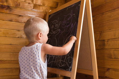 Young artist. Little boy drawing with chalk on a blackboardの写真素材