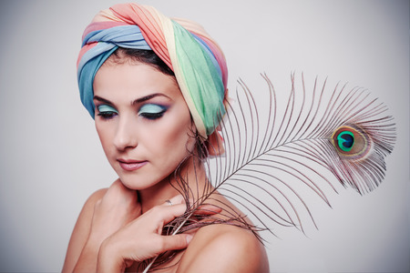 Portrait of young beautiful woman in a turban and peacock feather in oriental styleの写真素材