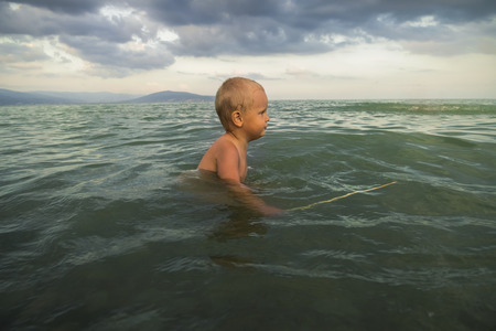 The little boy bathes in the sea near the shoreの写真素材