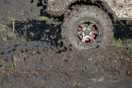 The wheels of car go round on dirt road.