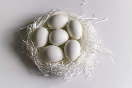 White easter egg in a silver wrapper in the nestの写真素材