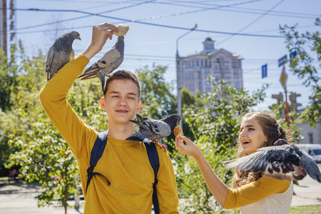 Couple teenagers feeding pigeons on city street summer dayの写真素材