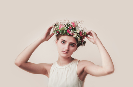 Pretty young girl wears a floral wreath of rosesの写真素材
