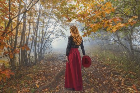 Beautiful red-haired woman with a red hat in the autumn park, photo collageの写真素材
