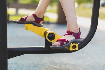 Outdoor gym: Legs of a girl on a public outdoor exercise bikeの写真素材