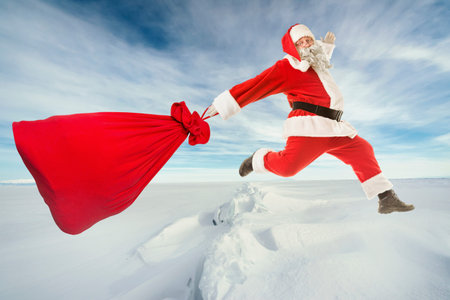 Santa Claus with a big bag of gifts lands on the frozen ice of the lakeの写真素材
