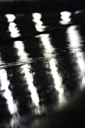Bright streaks of light on a black background glare of light on water black and white photoの写真素材