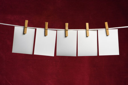 five white slip of paper attach to rope clothes peg on red