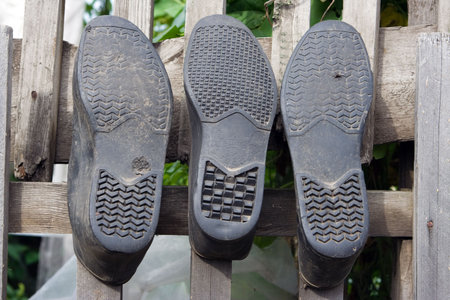 old rubber three galosh on wooden fenceの写真素材