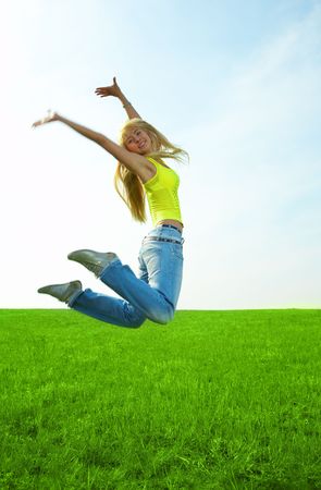 happy  young woman jump in field with green grassの写真素材