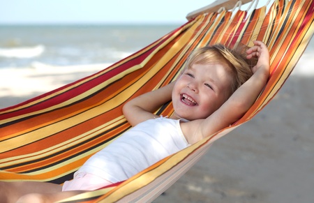 child relaxing in a hammock on the sea beachの写真素材