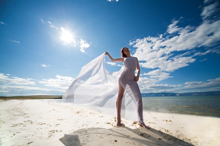 woman in white on coast of sea under blue sky with cloudsの写真素材