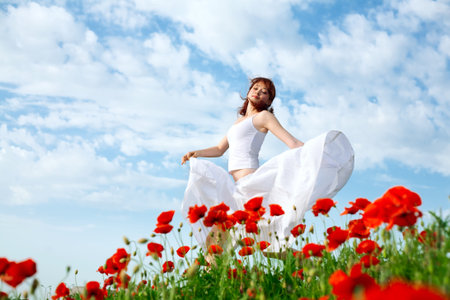 beauty woman in poppy field in white dressの写真素材
