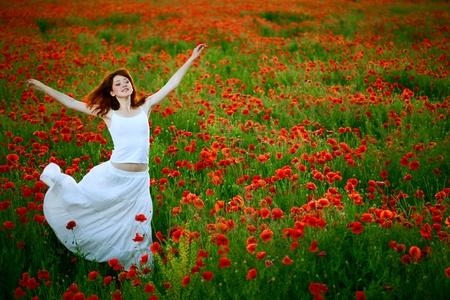 beauty woman in white dress running poppy fieldの写真素材