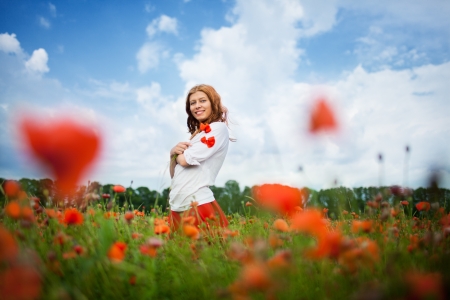beauty redheaded woman in poppy fieldの写真素材