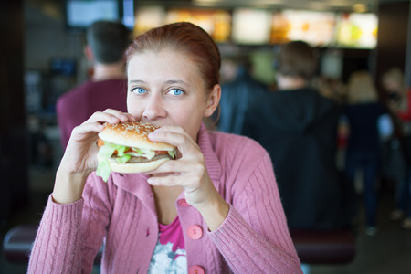beauty woman in cafe eating hamburgerの写真素材