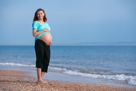 beauty pregnant woman on sea beach under blue skyの写真素材