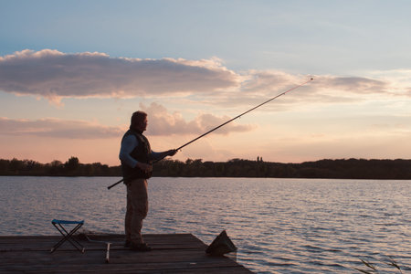 man fishing in sunset on pond