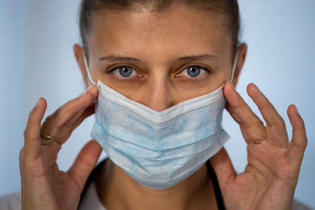 Medical doctor woman in special medical clothes in a protective mask on her face from coronavirus and a stethoscope around her neckの写真素材