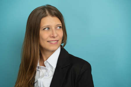 Beautiful Adult Business Woman Black Suit White Shirt Stands On Blue Backgroundの写真素材