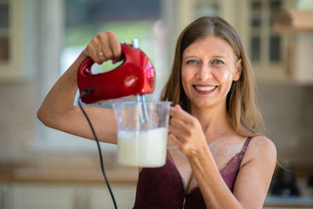 Beautiful sexy woman in lingerie in the kitchen at homeの写真素材