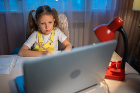Schoolgirl girl studies online on a laptop at home. Communicate online with a teacher. Teaching...