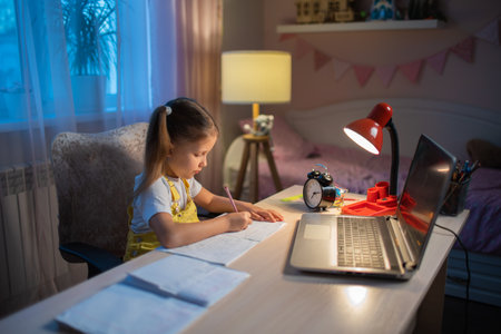 Schoolgirl girl studies online on a laptop at home. Communicate online with a teacher. Teaching lessons from school at the computer. Participation in distance education.の写真素材