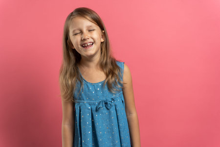 Little beautiful child girl in blue dress on pink background