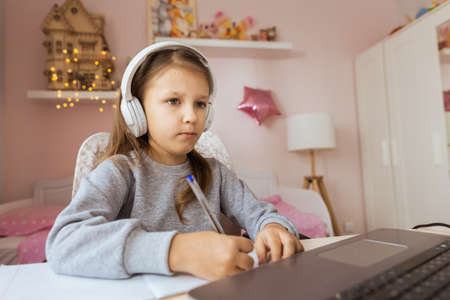 Schoolgirl Girl Studies Online On Laptop At Home. Communicate Online With Teacher. Teaching Lessons From School At Computer. Participates in distance education.の写真素材