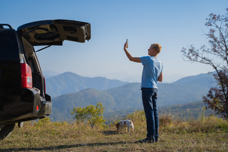 A young man is resting in nature with an off-road vehicle and a jack russell terrier dog. Uses a...