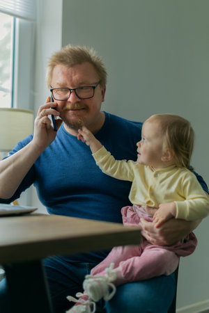 A freelance man father tries to work at home on a computer on the Internet and sits with a small child who prevents him from doing businessの写真素材