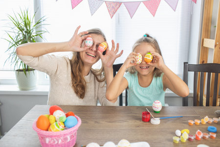 Mom and daughter are painting eggs for the bright holiday of Easter. Sit for happy with paints