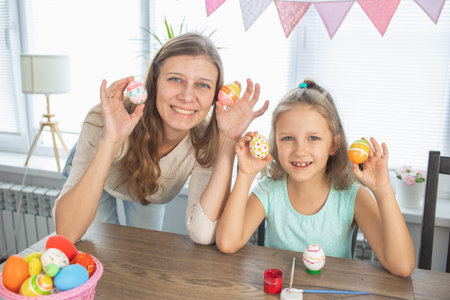 Mom and daughter are painting eggs for the bright holiday of Easter. Sit for happy with paints