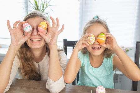 Mom and daughter are painting eggs for the bright holiday of Easter. Sit for happy with paints