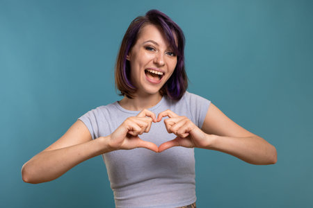 A beautiful young brunette girl in a T-shirt and breeches on a blue background shows different...