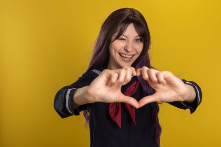 Beautiful young brunette girl in the uniform of a Japanese schoolgirl on a yellow background