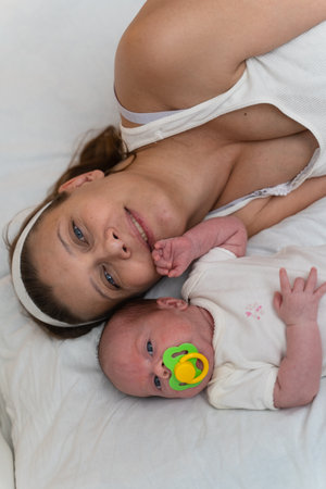 Mother with a newborn baby in the bedroom on the bed at homeの写真素材