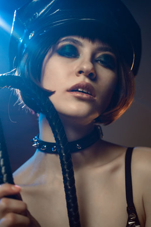 Beautiful Sexy Woman In Erotic Clothing For BDSM Domination In The Rays Of Light And Smoke