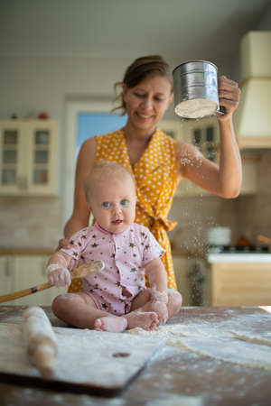 Woman mother with little toddler in the kitchen cook from flour and have fun having funの写真素材