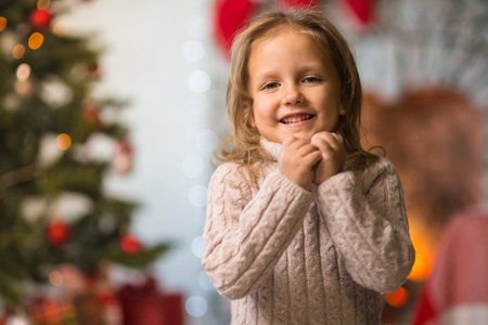 Little girl child at home at the fireplace celebrates Merry Christmas with giftsの写真素材