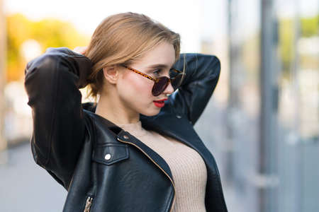 Young beautiful woman walks through city streets between building with sunglassesの写真素材