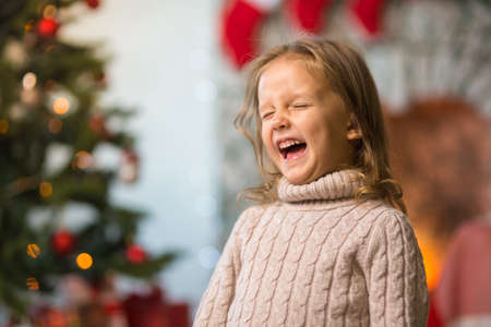 Little girl child at home at the fireplace celebrates Merry Christmas with giftsの写真素材