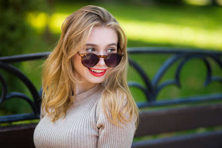 Young beautiful woman walks through city streets between building with sunglassesの写真素材